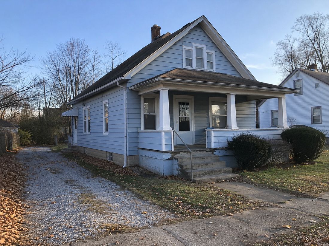 A blue craftsman home with a gravel drive