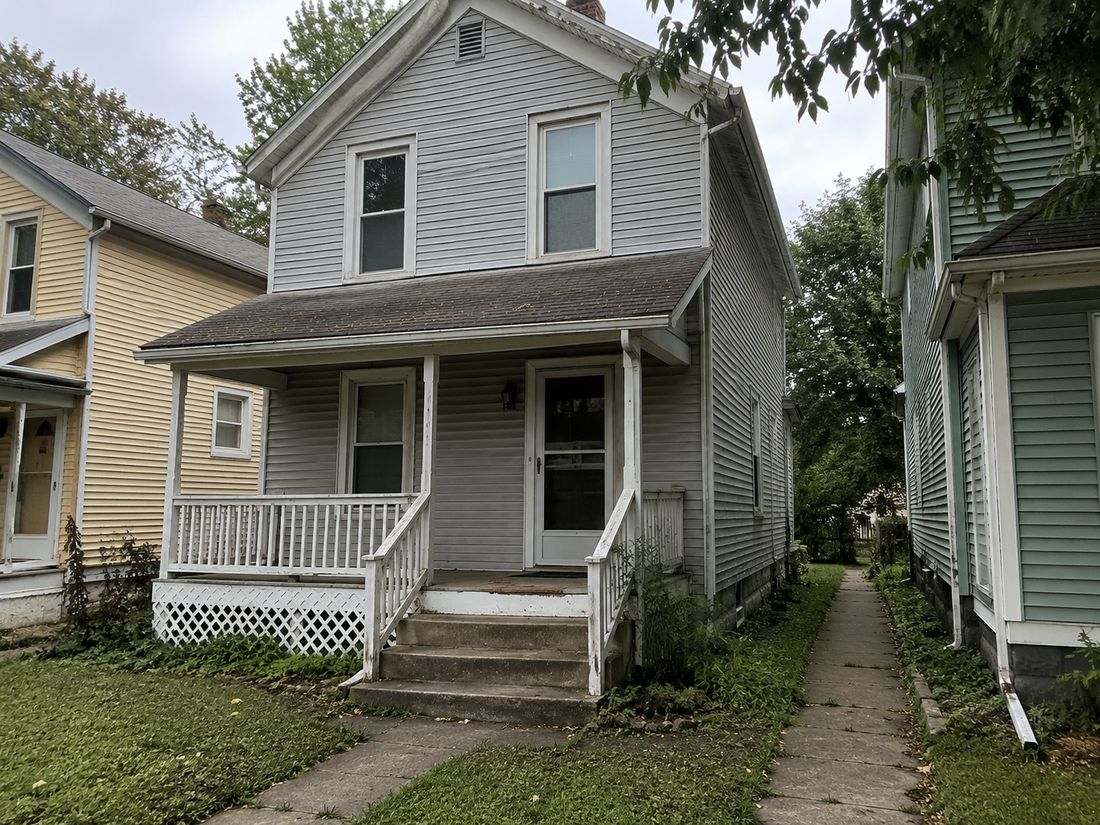 A narrow two-story home with a front porch
