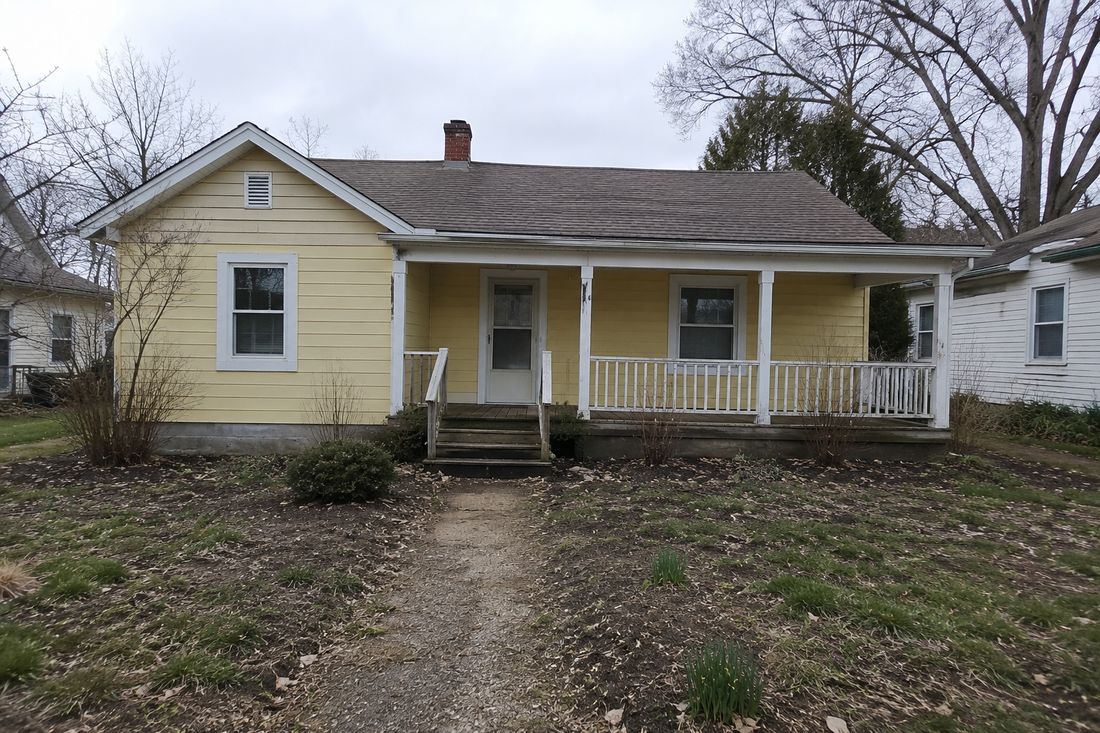A yellow cottage with a covered front porch